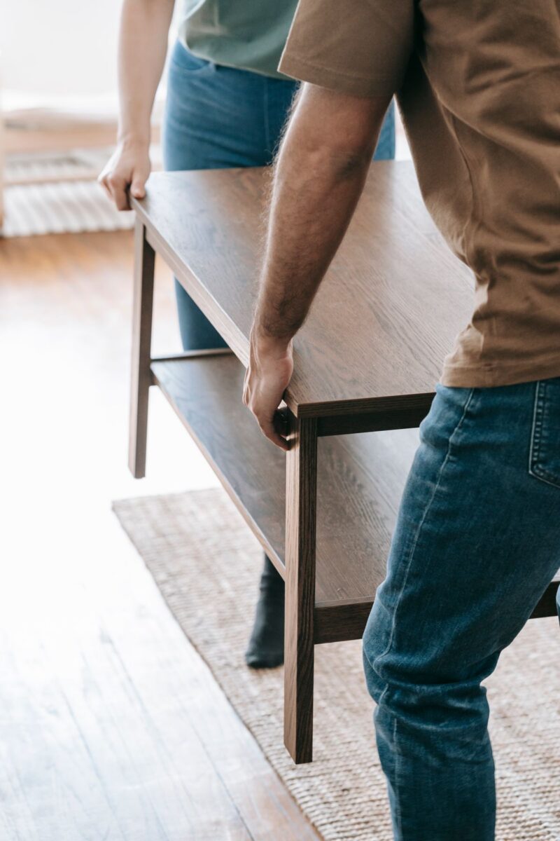 Two-person Proovia delivery crew carrying a wooden table